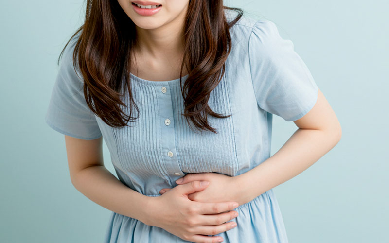 下腹部を押さえて苦しそうな女性の画像